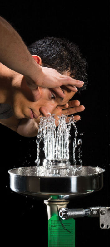 Person leaning over an AXION MSR stainless steel eye/face wash station